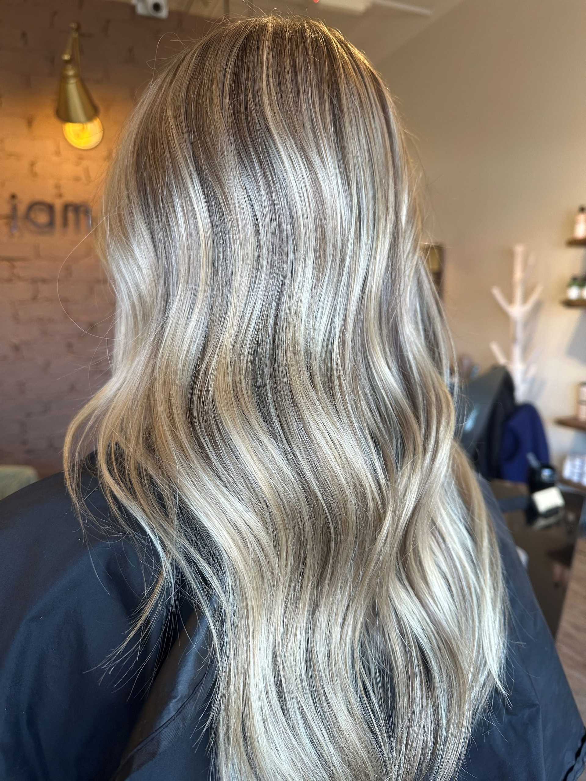 Blonde hair with soft waves at a salon, showcasing a fresh hairstyle from behind.