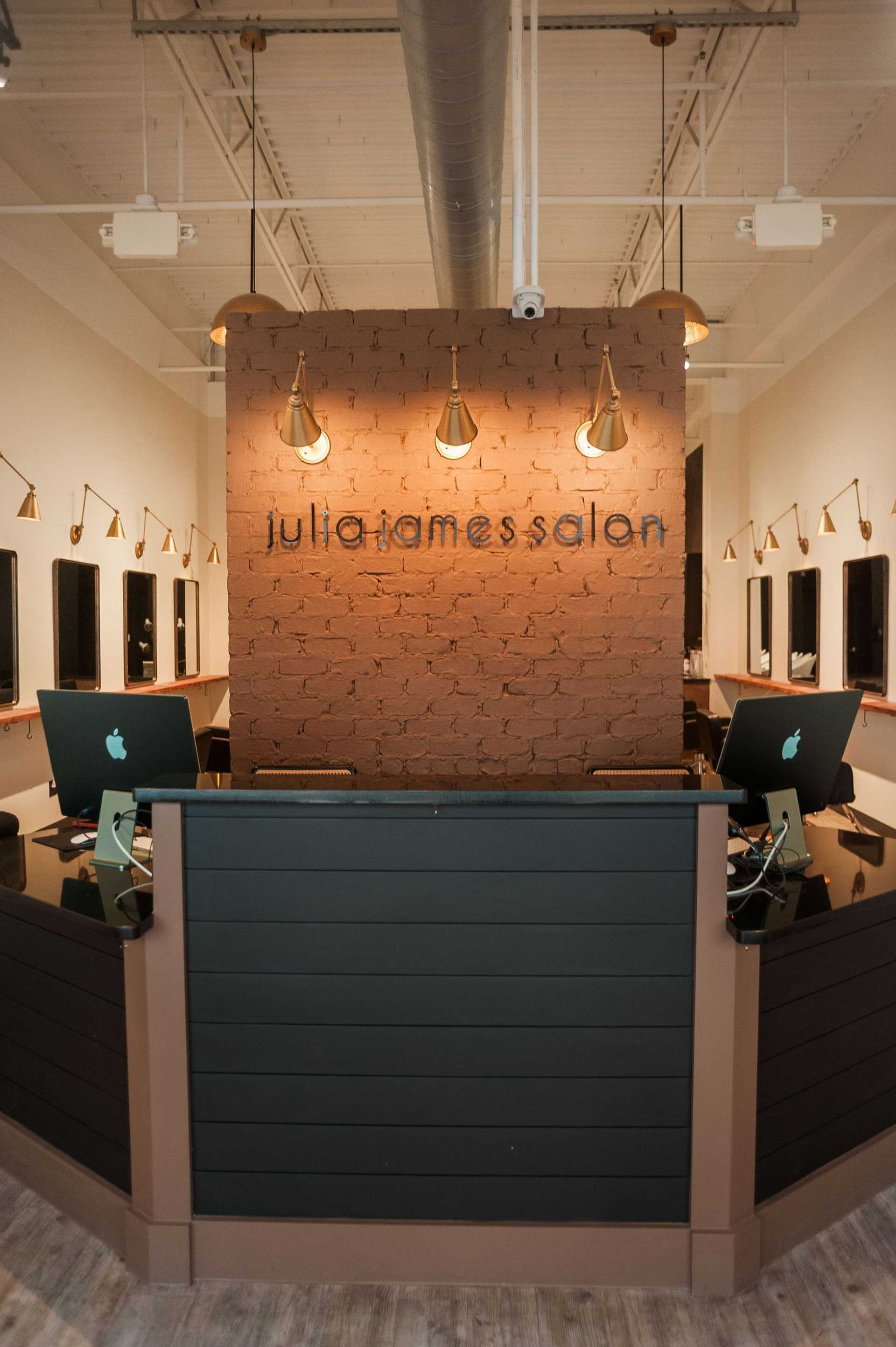 Modern salon reception area with wooden accents, two computer desks, and stylish lighting fixtures.